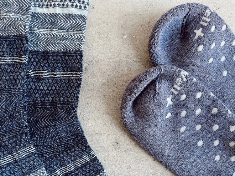 TWO PAIRS OF SOCKWELL SOCKS LAY ON CONCRETE FLOORS, ONE HAS STRIPES AND PATTERED, ONE HAS POLKA DOTS