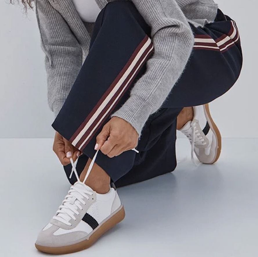 person sitting on tree stump wearing white vionic sneakers